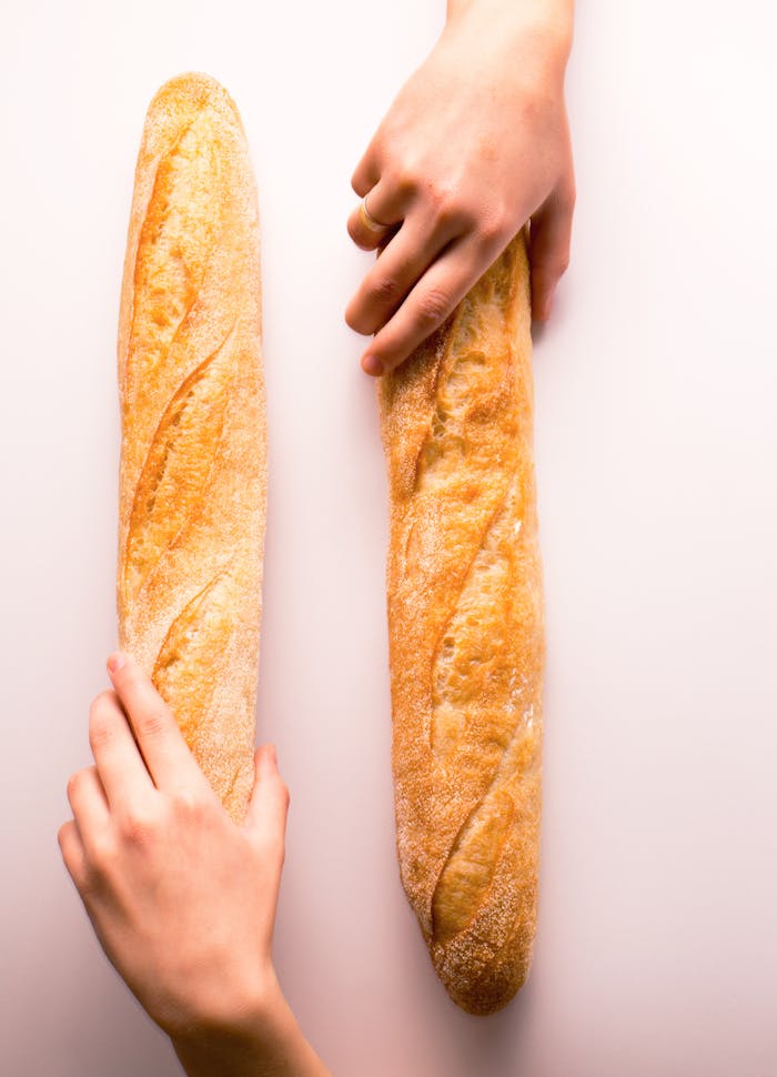 Two hands grasping fresh baguettes on a white background. Perfect for bakery or bread-themed visuals.
