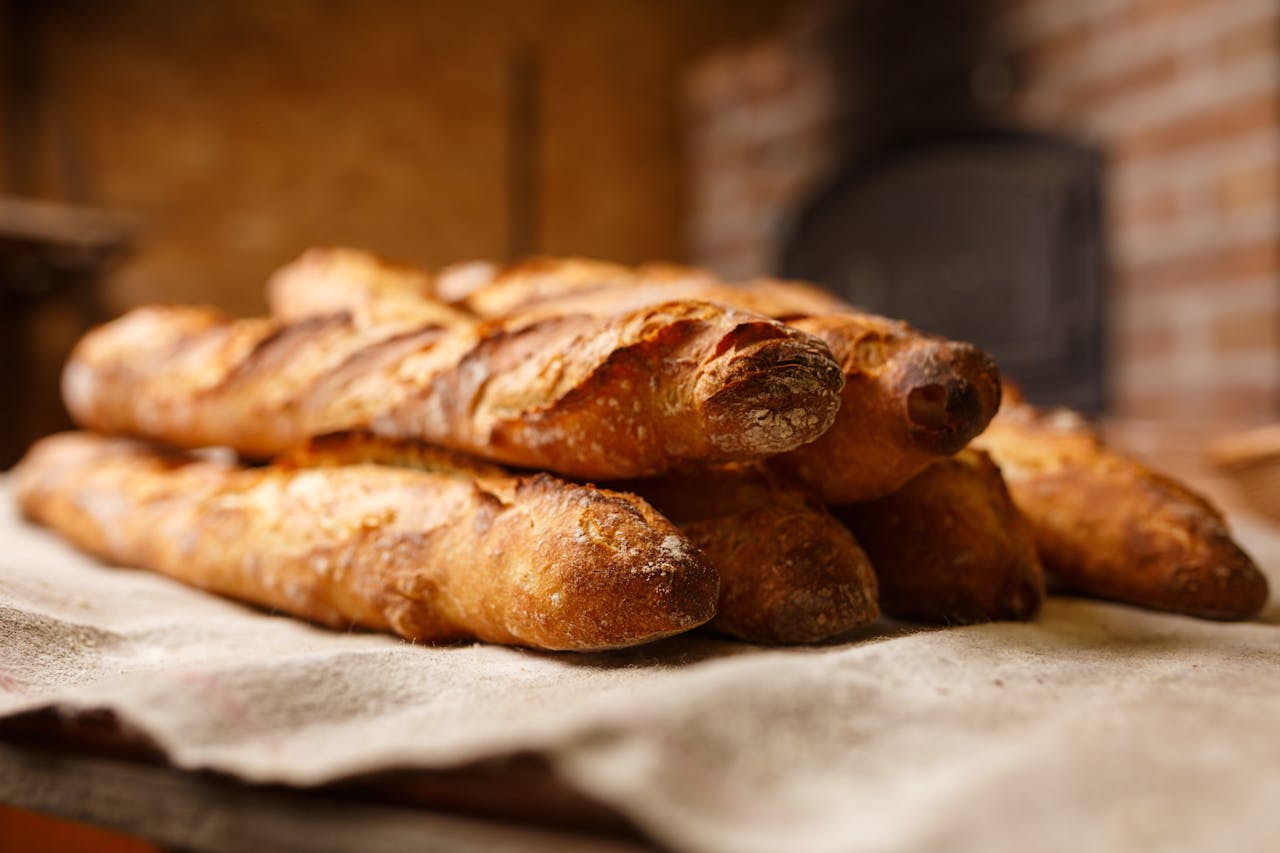Warm, freshly baked rustic baguettes stacked in a cozy bakery setting.